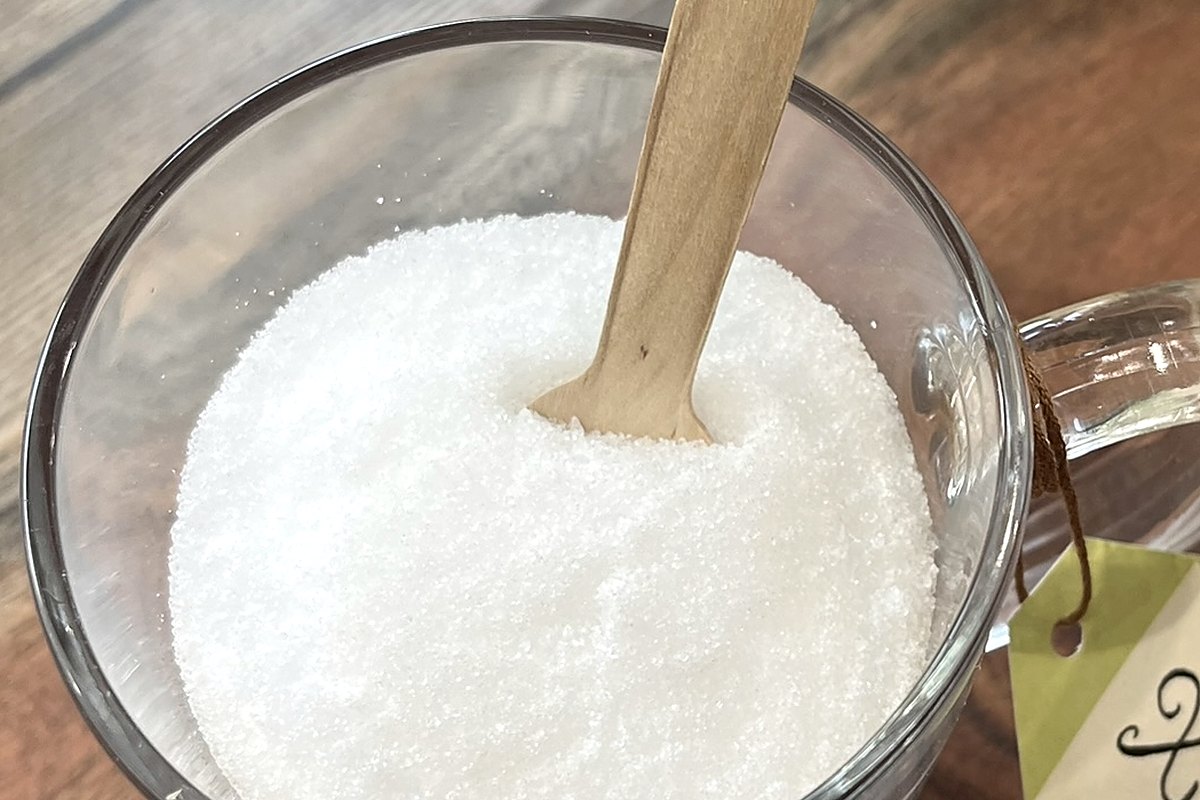 Gros plan sur les cristaux de xylitol dans une tasse en verre, un bâtonnet de bois planté au centre